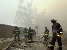 New York City firefighters work amid debris in this Sept. 11, 2001, photo, with the skeleton of the World Trade Center twin towers in the background.