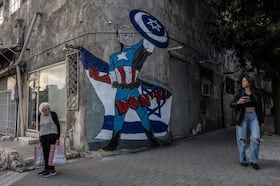 Sabrina Viener, 84, who immigrated to Israel from Romania 50 years ago, looks at graffiti showing President Biden on a building in Tel Aviv on Sunday.