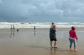 Families explore the rough surf along Matagorda Beach ahead of Beryl’s arrival.